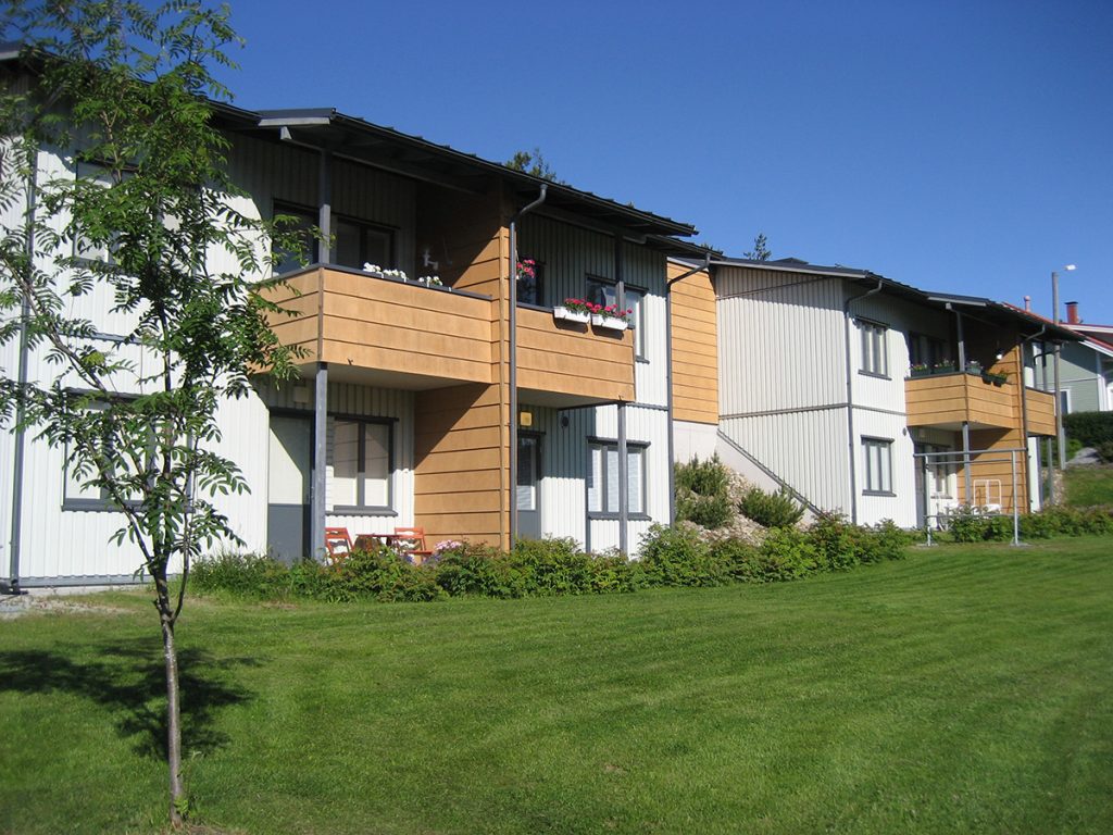 Kaksikerroksinen talo ja etualalla nurmikkoa.