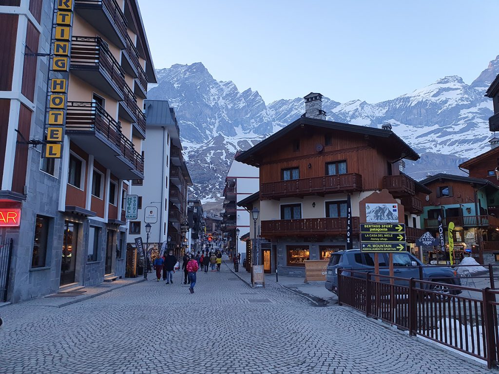 Talot reunustavat Cervinian kylän läpi viemää pääkatua ja taustalla näkyvät korkeat vuoret