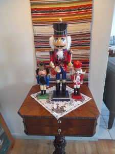 Pöydällä kolme puista pähkinänsärkijänukkea, joista keskimmäinen pisin ja molemmilla puolilla vierellä huomattavasti pienemmät nuket