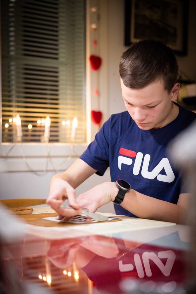 Tuomas Järvinen asettelee piparkakkutalon seinän mallia taikinan päälle pöydän ääressä