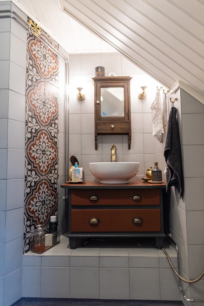 Wc-tilassa on peilikaappi seinällä ja vanhasta puulipastosta madallettu allaskaappi