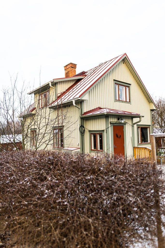 Vaaleanvihreä puutalo, jonka ympärillä pieni puutarha