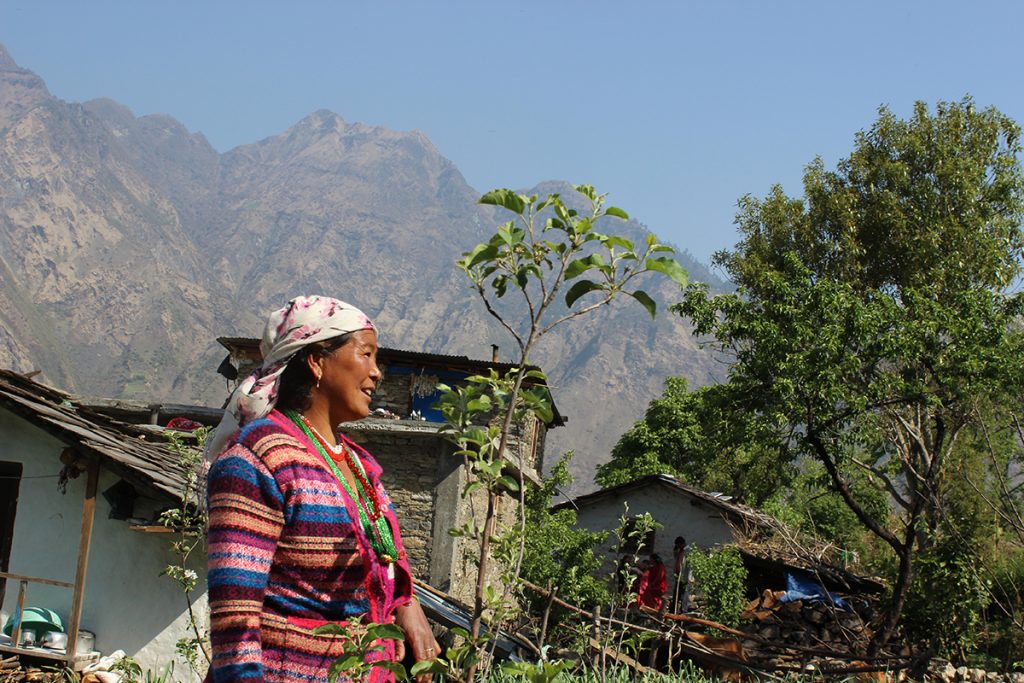 Nainen seisoo ulkona rakennuksen ja puutarhan edustalla